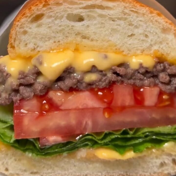A classic NYC chopped cheese sandwich wrapped in butcher paper, showing the melty beef and cheese filling.