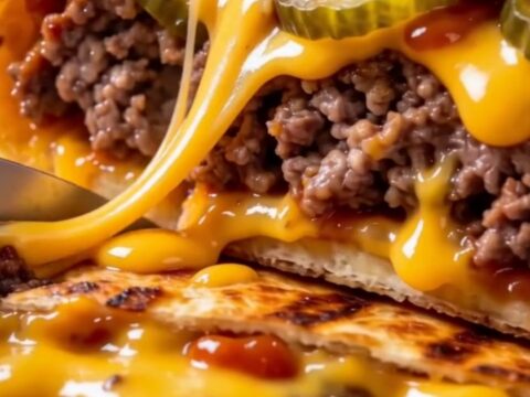 A crispy, golden-brown smash cheeseburger wrap sliced in half on a wooden board, showing layers of beef and melted cheese.
