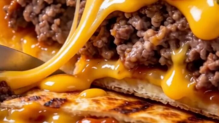 A crispy, golden-brown smash cheeseburger wrap sliced in half on a wooden board, showing layers of beef and melted cheese.