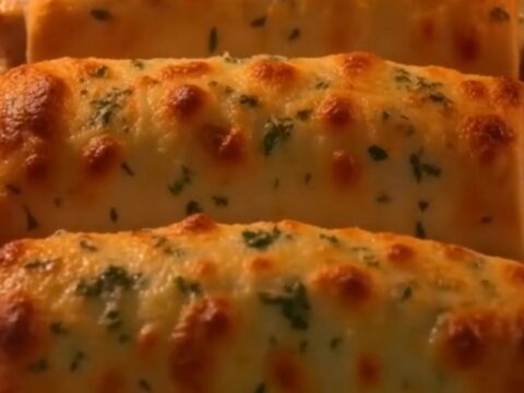 A close-up of a crispy baked chicken roll-up sliced in half, showing a gooey, melted mozzarella and cream cheese filling.