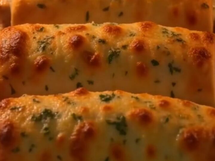 A close-up of a crispy baked chicken roll-up sliced in half, showing a gooey, melted mozzarella and cream cheese filling.