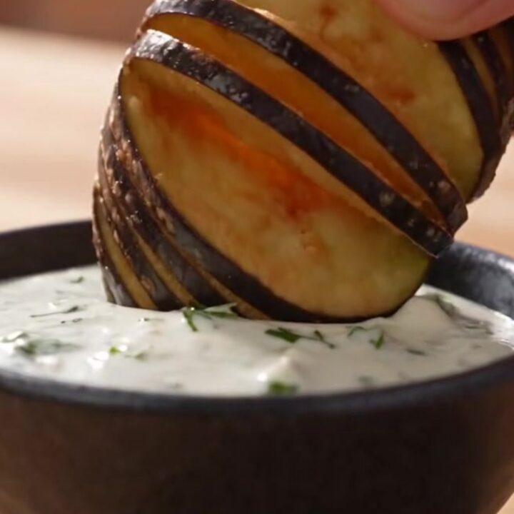 Golden brown fan-cut accordion eggplant fries arranged on a rustic platter.