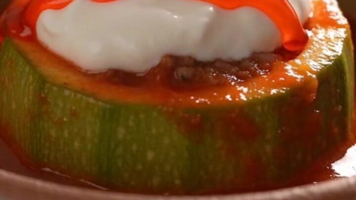 A close-up view of a tender, glazed round zucchini bowl sitting in a bubbling, rich red tomato sauce.
