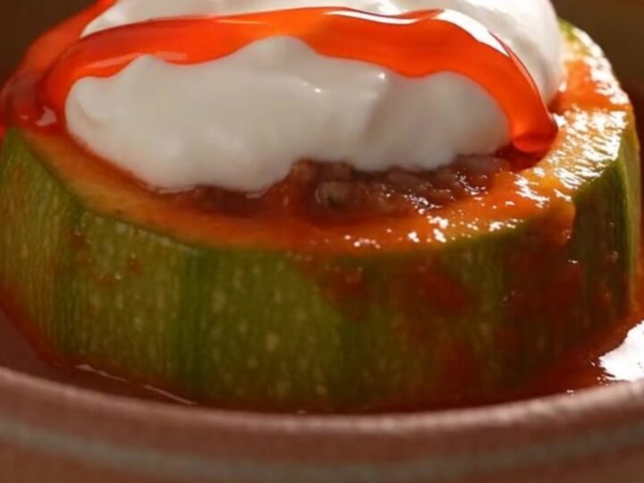 A close-up view of a tender, glazed round zucchini bowl sitting in a bubbling, rich red tomato sauce.