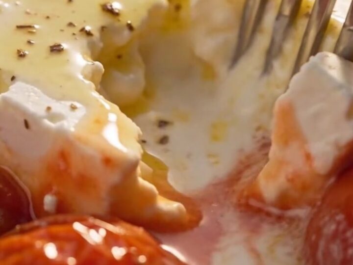 A serving spoon lifts a steaming portion of tender shell pasta covered in a rich pink tomato-cream sauce with melted feta.