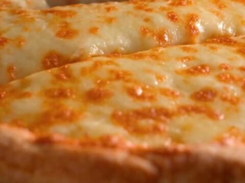 A golden baked tortilla casserole pie in a cast iron pan with a slice being lifted to show a massive cheese pull.