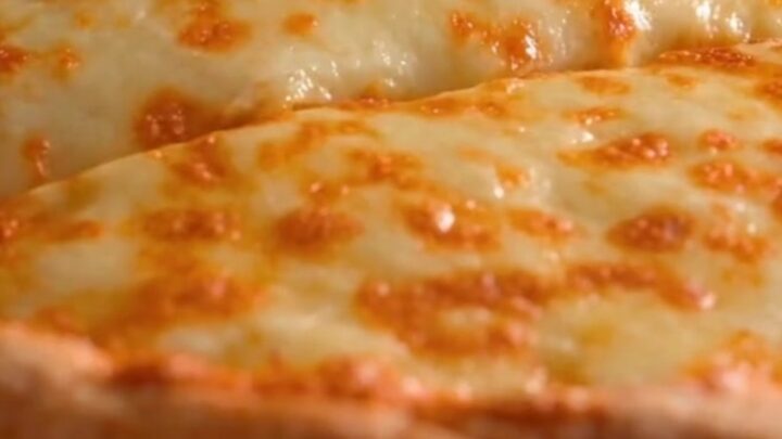 A golden baked tortilla casserole pie in a cast iron pan with a slice being lifted to show a massive cheese pull.