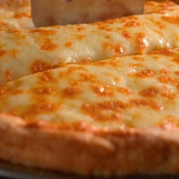 A golden baked tortilla casserole pie in a cast iron pan with a slice being lifted to show a massive cheese pull.