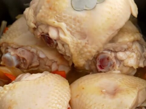 A top-down view of a slow cooker filled with chicken thighs, colorful bell peppers, and red onions ready to be cooked.