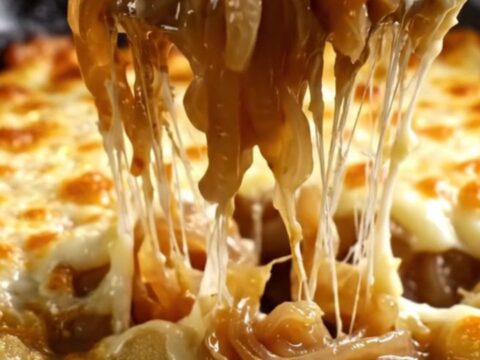 A cast-iron skillet filled with gnocchi in a rich onion broth, covered with a bubbly, golden-brown Gruyère cheese crust.