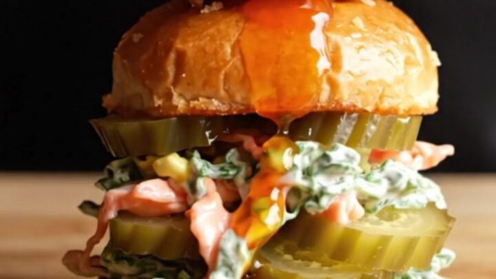 A close-up of a Nashville hot chicken slider with visible honey butter dripping down the side.