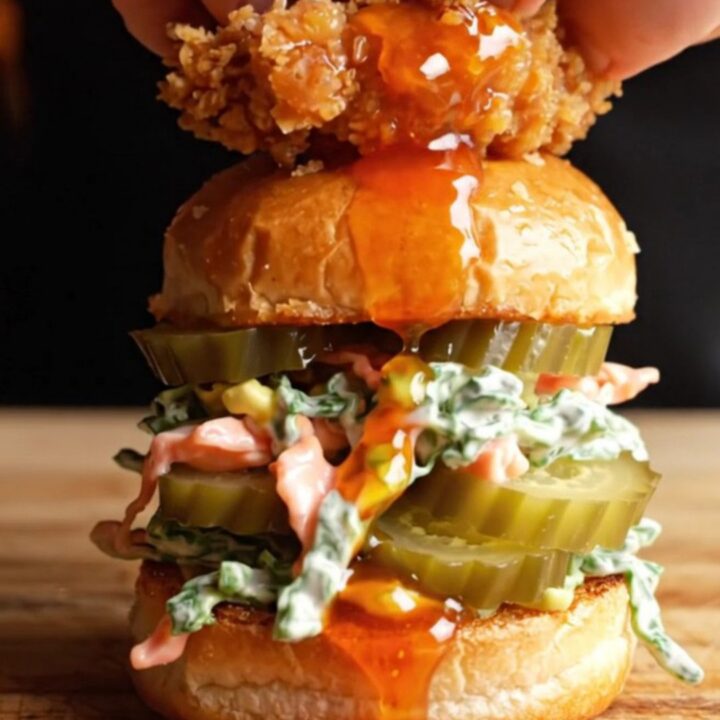 A close-up of a Nashville hot chicken slider with visible honey butter dripping down the side.