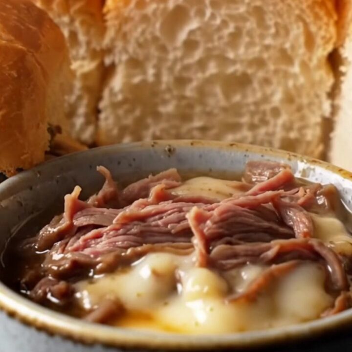 A stack of pull-apart French dip sliders with melted provolone and caramelized onions