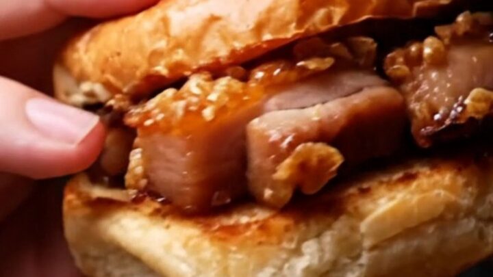 A close-up shot of a crispy pork belly slider with a glossy hoisin glaze on a toasted brioche bun.