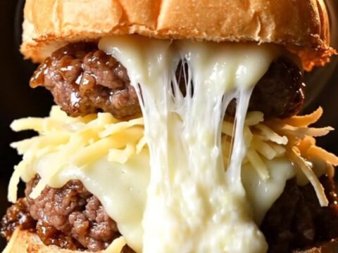 A close-up of a Korean bulgogi slider with melted mozzarella and scallions on a soft milk bun.