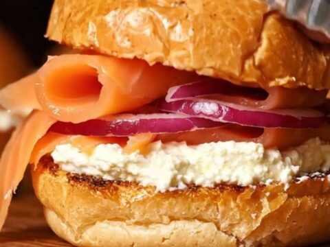 A close-up of everything bagel smoked salmon sliders on a wooden board.