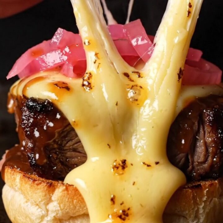 A close-up of a smoked brisket burnt ends slider with melted Gouda cheese and a glossy barbecue glaze.