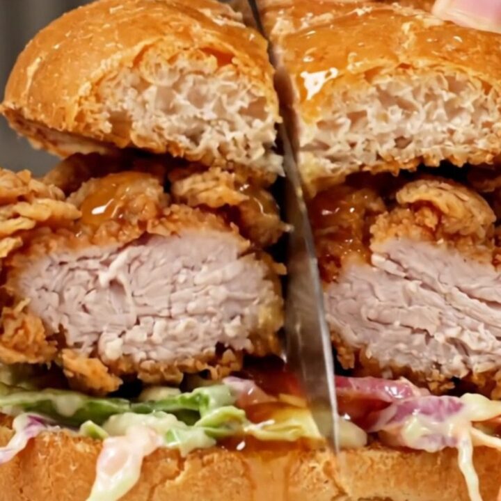 A crispy golden-fried chicken breast sandwich on a toasted bun with fresh slaw and a glistening hot honey glaze.