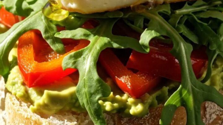 Close-up of a golden-seared halloumi sandwich on ciabatta with avocado and honey drizzle.