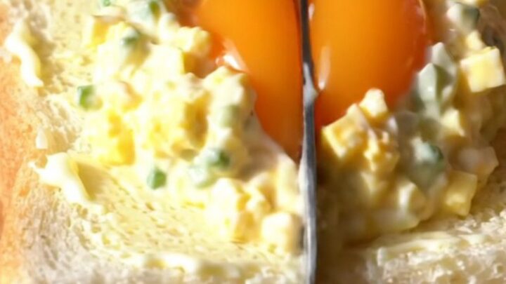 A close-up view of a Japanese Tamago Sando sandwich showing a creamy egg salad filling and a jammy egg center.