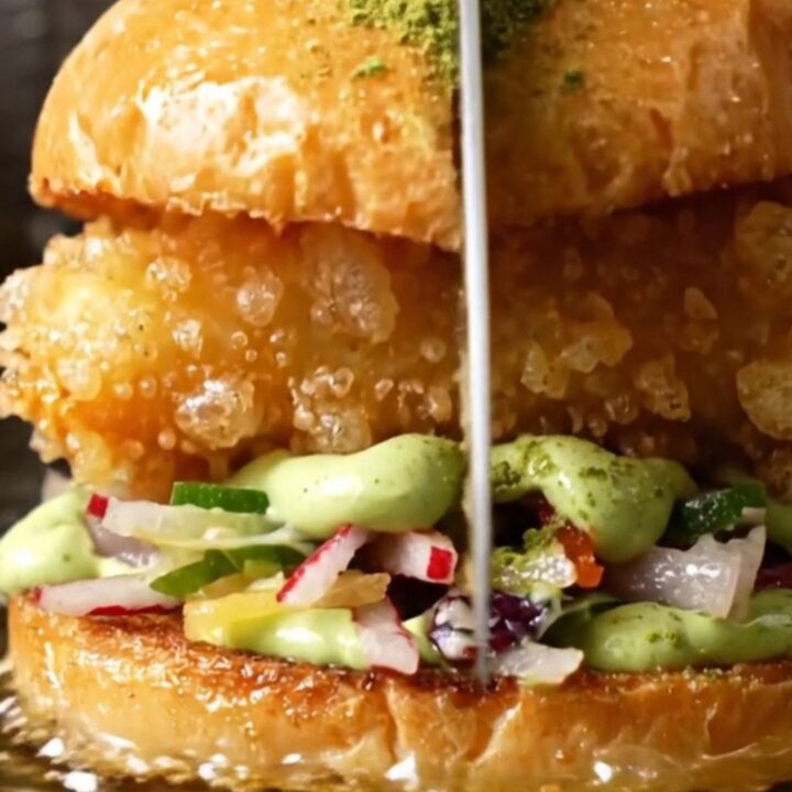 A close-up of a crispy tempura soft-shell crab sandwich on a toasted brioche bun with radish slaw.