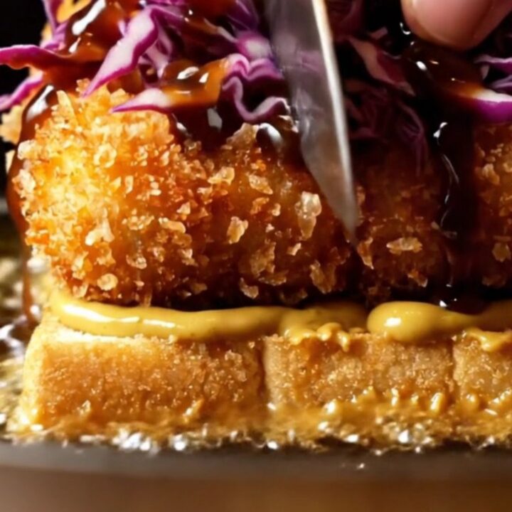 A close-up view of a crispy tofu katsu sando on toasted milk bread with curry mayo.