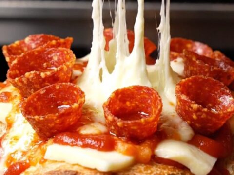 A close-up of a pull-apart pepperoni pizza garlic bread loaf with melted mozzarella and crispy pepperoni.