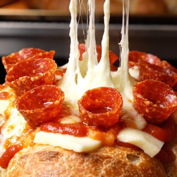 A close-up of a pull-apart pepperoni pizza garlic bread loaf with melted mozzarella and crispy pepperoni.