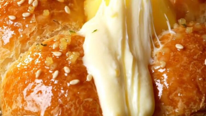 A close-up shot of a golden Korean cream cheese garlic bun with cream cheese oozing out of a pulled-apart wedge.