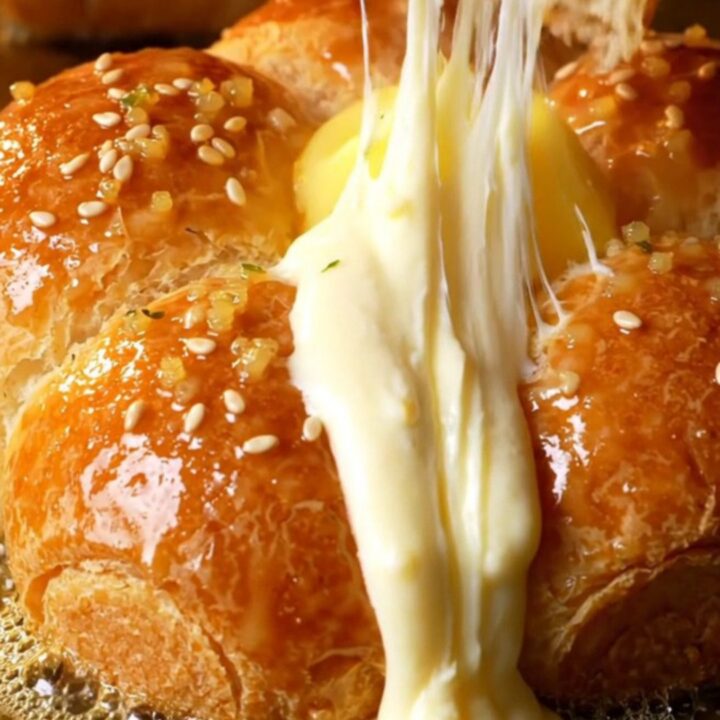 A close-up shot of a golden Korean cream cheese garlic bun with cream cheese oozing out of a pulled-apart wedge.