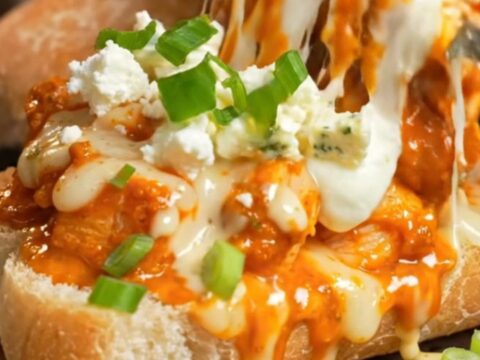 A close-up of a spicy buffalo chicken and Gorgonzola cheesy garlic ciabatta loaf with a cheese stretch.