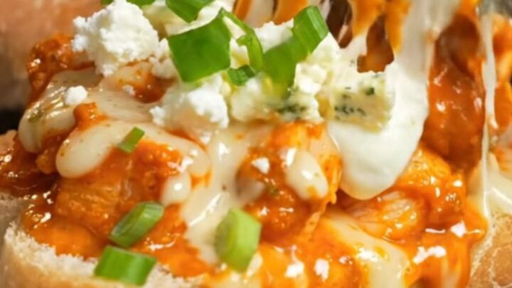 A close-up of a spicy buffalo chicken and Gorgonzola cheesy garlic ciabatta loaf with a cheese stretch.