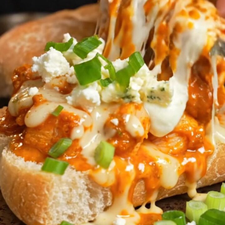 A close-up of a spicy buffalo chicken and Gorgonzola cheesy garlic ciabatta loaf with a cheese stretch.