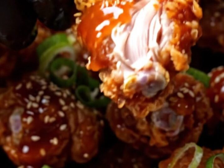 Cinematic close-up of crispy Korean wings glistening with a vibrant red gochujang glaze and sesame seeds.