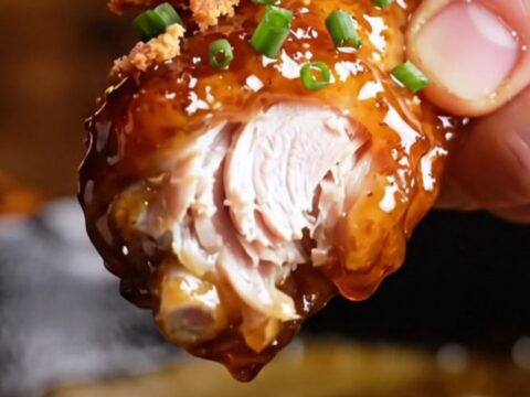 A close-up shot of crispy chicken wings coated in a shiny, dark mahogany chipotle maple bourbon glaze.