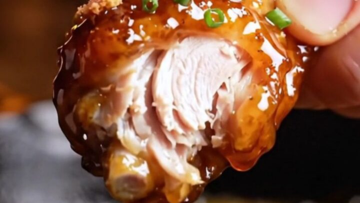 A close-up shot of crispy chicken wings coated in a shiny, dark mahogany chipotle maple bourbon glaze.