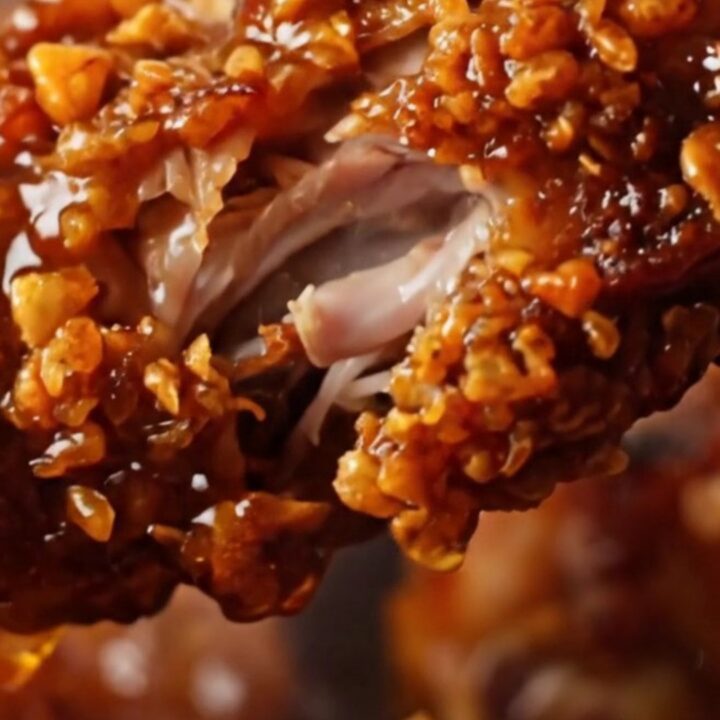 A close-up of crispy, charred Jamaican jerk chicken wings on a cast-iron pan with a glossy glaze.