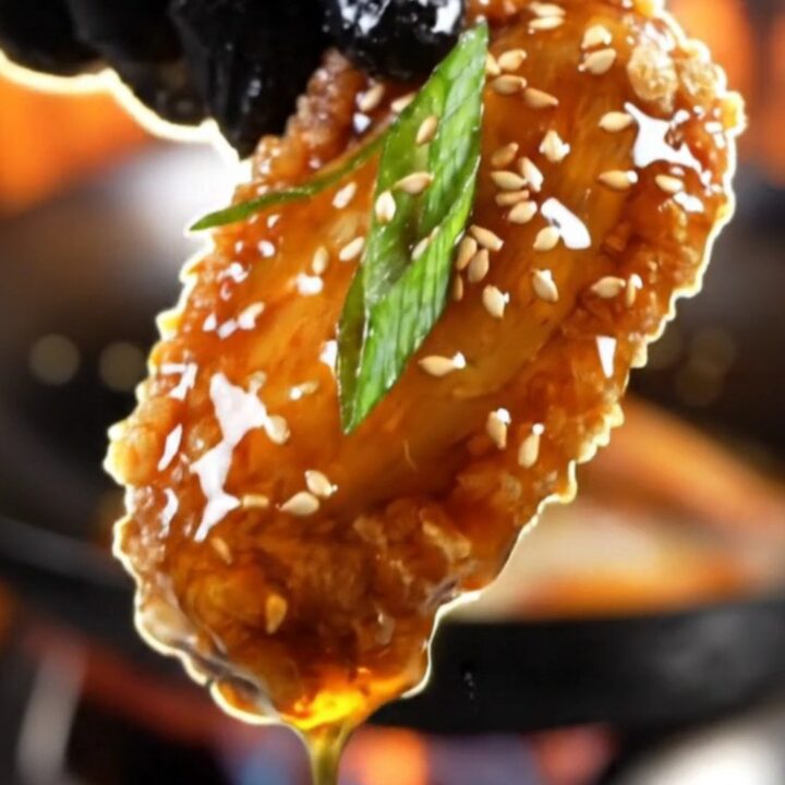 Crispy General Tso's chicken wings coated in a glossy dark glaze and topped with sesame seeds.