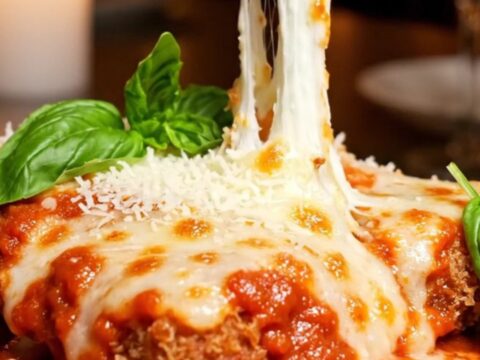 A crispy, golden-fried chicken parmigiana bombe topped with bubbly melted cheese and fresh basil.