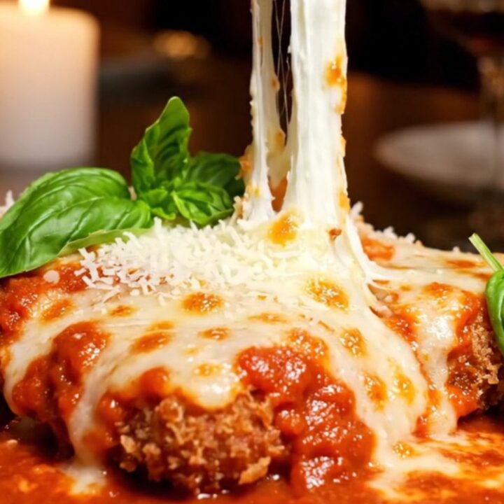 A crispy, golden-fried chicken parmigiana bombe topped with bubbly melted cheese and fresh basil.