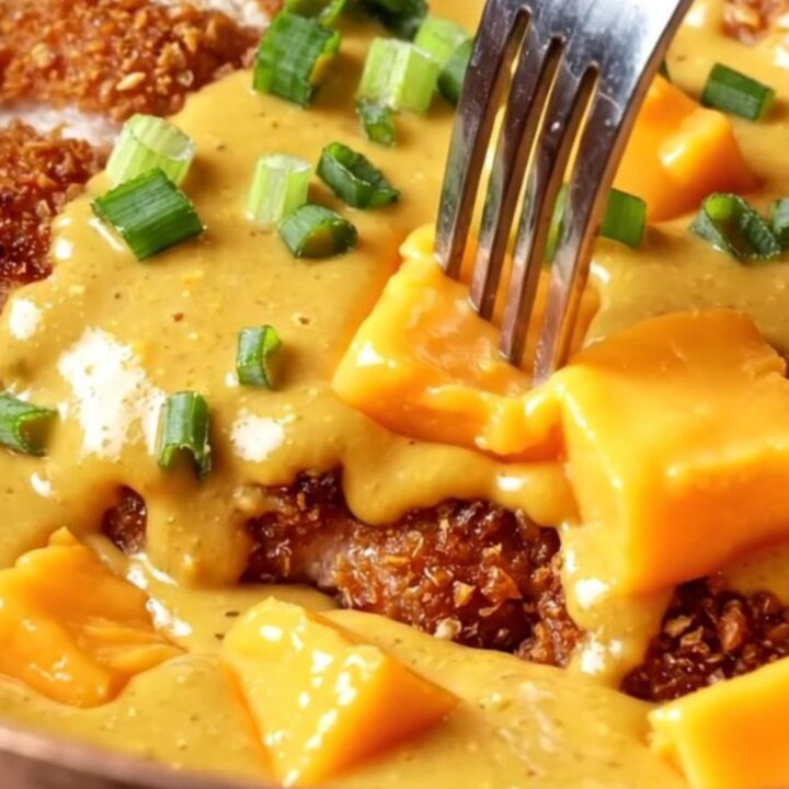 A golden, crispy pretzel-crusted chicken cutlet drizzled with a rich, molten sharp cheddar beer cheese sauce.