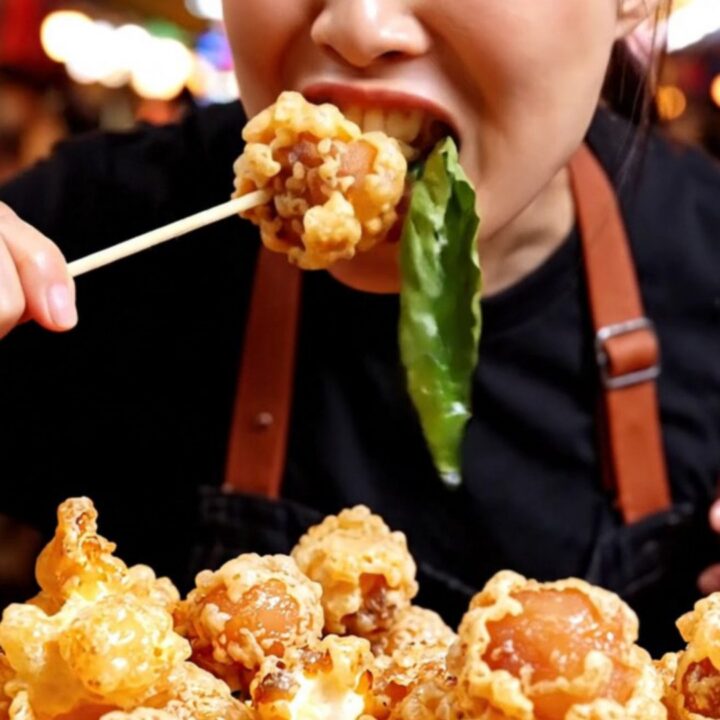 A close-up of golden-brown Taiwanese popcorn chicken with crispy green Thai basil leaves.