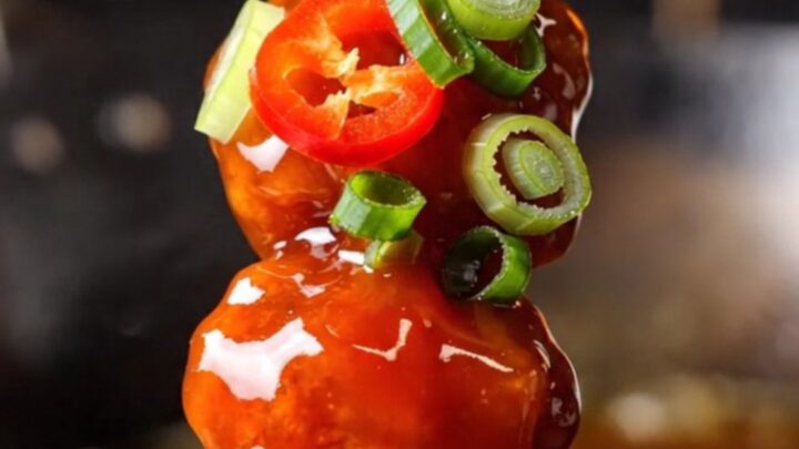 Macro close-up of crispy firecracker chicken bites with a glossy red sauce.