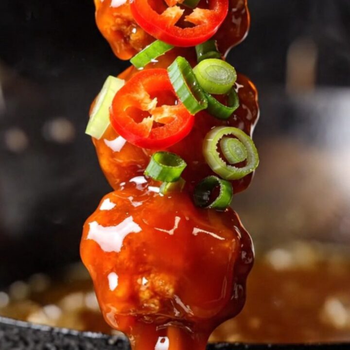 Macro close-up of crispy firecracker chicken bites with a glossy red sauce.