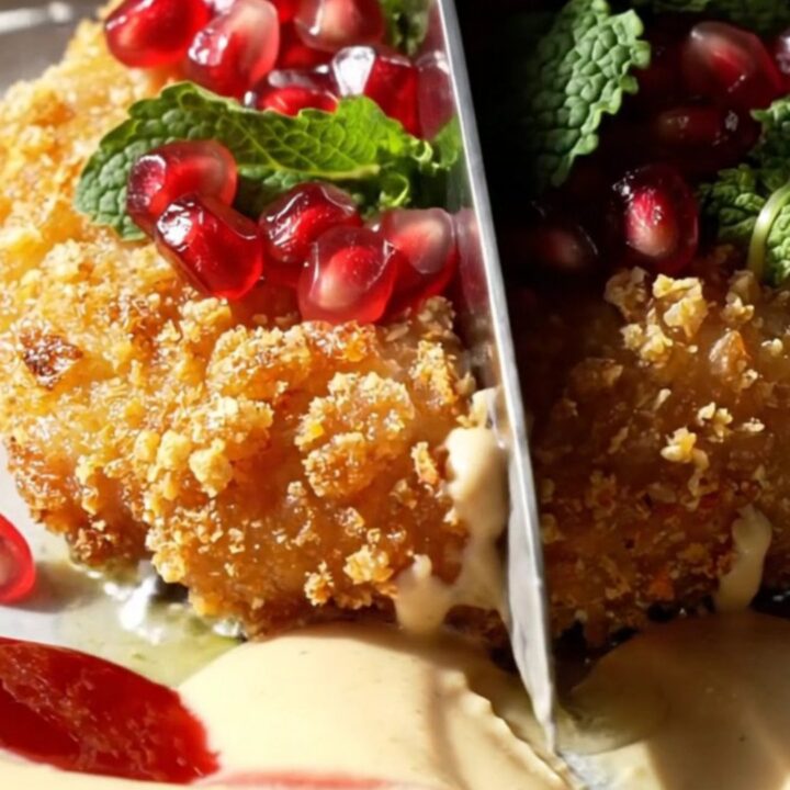 A crispy golden-brown za'atar chicken cutlet drizzled with white garlic tahini and topped with red pomegranate seeds.