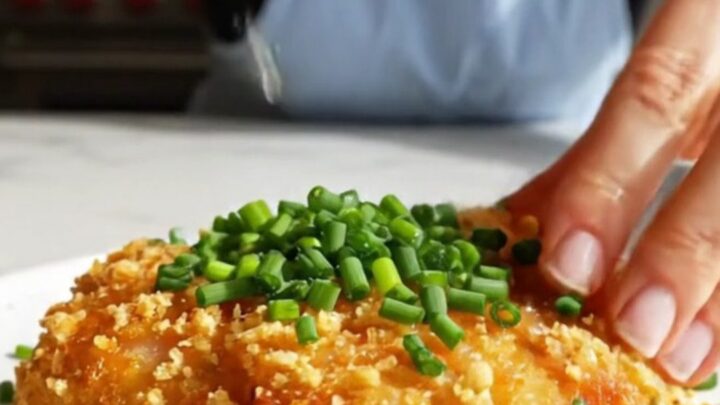 A close-up of a golden-brown, crispy kettle chip crusted chicken cutlet on a plate.
