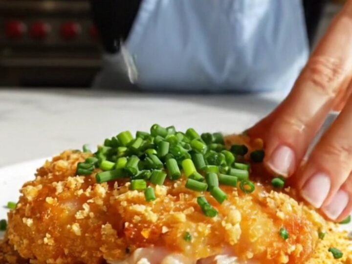 A close-up of a golden-brown, crispy kettle chip crusted chicken cutlet on a plate.