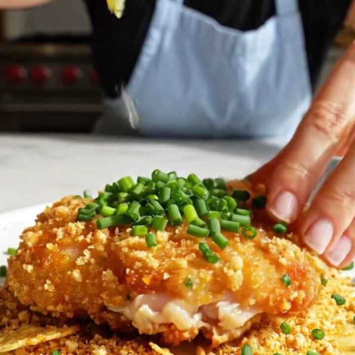 A close-up of a golden-brown, crispy kettle chip crusted chicken cutlet on a plate.