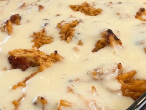 A glass baking dish filled with golden seasoned rice and shredded chicken, smothered in a thick layer of melted white queso.