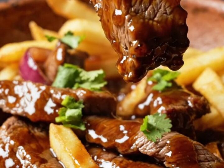 A vibrant plate of Peruvian lomo saltado featuring charred beef strips, blistered onions, and golden fries.